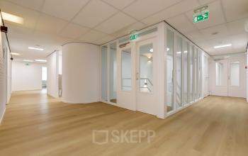 Bright, unfurnished open floor plan at Bruningweg 23, Arnhem IJsseloord, featuring light wooden floors and glass-panel doors, ideal for office space rental.