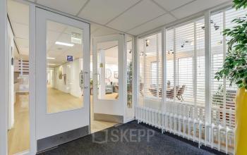 Interior view of office located at Bruningweg 23, Arnhem IJsseloord, featuring a hallway with glass doors and plants, ideal for those seeking office space rental.