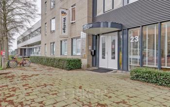 The exterior of an office building at Bruningweg 23, Arnhem IJsseloord, featuring a modern entrance with glass doors and a sign, suitable for office space rental.