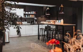 A modern pantry area with high stools and a table. Perfect for casual meetings in Vlamoven 34, Arnhem IJsseloord, offering versatile office space rental.