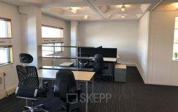 Modern furnished office space rental at Simon Stevinweg 27, Arnhem Oost, featuring multiple desks, chairs, and ample natural light through large windows.