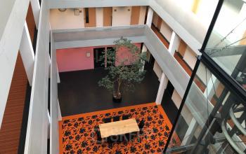Open atrium view with central table, patterned orange carpet, and a tree at Simon Stevinweg 27, Arnhem Oost ideal for office space rental.