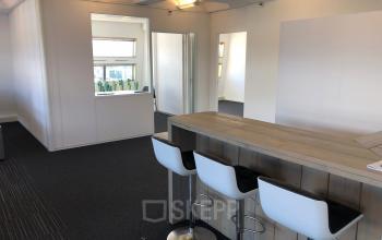 Modern office space rental at Simon Stevinweg 27, Arnhem Oost, Arnhem, featuring a high table with bar stools and workspace areas.