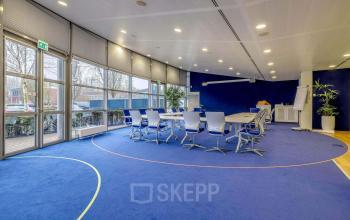 Bright conference room with blue carpet, large windows, and a central table with white chairs at Meester D.U. Stikkerstraat 11, Arnhem Zuid, Arnhem.
