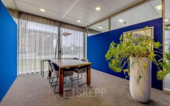 Office space at Meester D.U. Stikkerstraat 11, Arnhem Zuid, Arnhem, featuring a meeting table with chairs, a modern lamp, and a plant adding a touch of greenery.