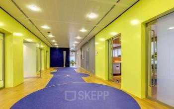 Interior hallway of an office building at Meester D.U. Stikkerstraat 11, Arnhem Zuid, Arnhem with vibrant yellow walls and blue circular carpets.