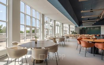 Spacious and bright office lounge area with round tables and modern chairs, located at Rijksweg-West 2, Arnhem Zuid, Arnhem, available for office space rental.