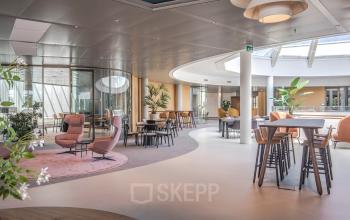 Modern office space rental at Rijksweg-West 2 in Arnhem Zuid featuring open floor plan with stylish seating, round tables, and natural lighting.