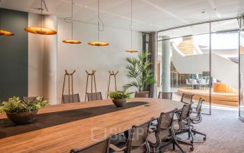 Modern conference room at Rijksweg-West 2, Arnhem Zuid, Arnhem, with a large wooden table, ergonomic chairs, and stylish lighting.