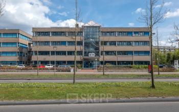Exterior view of the office building at Overcingellaan 17 in Assen, featuring a four-story structure with large windows and a central glass entrance. Ideal location for those seeking office space rental.