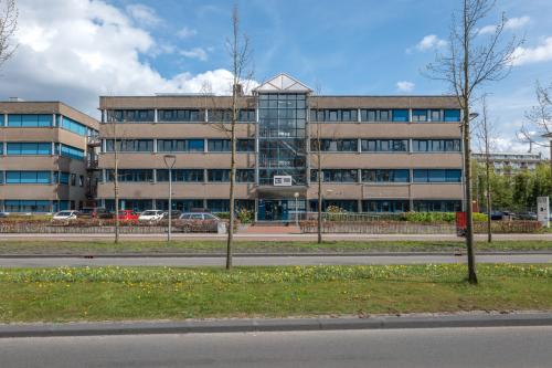 Exterior view of the office building at Overcingellaan 17 in Assen, featuring a four-story structure with large windows and a central glass entrance. Ideal location for those seeking office space rental.