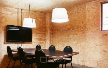 Office space rental at Carrer de Vilafranca 7 in Barcelona Gràcia, featuring a furnished room with a table, chairs, and wall-mounted TV, ideal for meetings.
