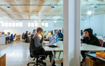Open office space in Barcelona Gràcia with professionals working at desks on laptops. Ideal for those looking to rent office space in a collaborative environment.