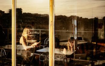 Two people at Carrer de Vilafranca 7, Barcelona Gràcia, are engaged in work activities, looking at laptops in an office to rent with a city view.