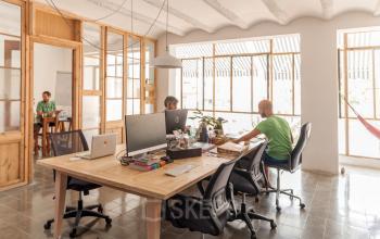 Spacious office at Carrer de Vilafranca 7, Barcelona Gràcia, featuring modern workspaces with desks and chairs, where people are actively working. Ideal for office space rental.