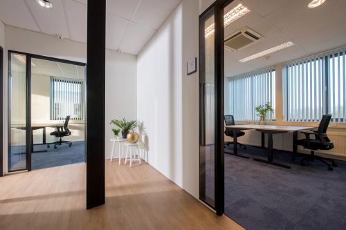 Bright and furnished office space to rent at Veemweg 29-31, Barneveld, featuring desks, chairs, and natural light through large windows.