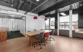 Modern gestalteter Büroraum mieten in Teichgässlein 9, Basel Altstadt Kleinbasel, mit Holztisch und bequemen Stühlen, beleuchtet durch große Fenster.