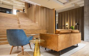 Bürofläche mieten in Basel Altstadt Kleinbasel am Barfüsserplatz 3. Der Raum ist modern gestaltet mit einer gemütlichen Sitzecke aus blauem und braunem Sessel.