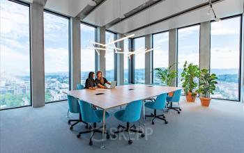 Moderne Bürofläche mieten in Grosspeteranlage 29, Basel St. Alban, mit Panoramafenstern und tagheller Beleuchtung, besetzt mit arbeitenden Personen.