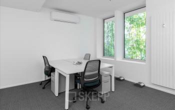 Heller Büroraum zum Mieten im Basel Stücki Village an der Hochbergerstrasse 70, ausgestattet mit Tisch und Stühlen neben einem Fenster.