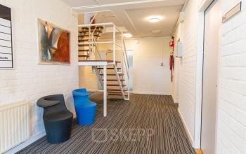 Interior view of office space at Middelweg 25, Beek Lb featuring modern seating and a staircase leading to the upper floor.