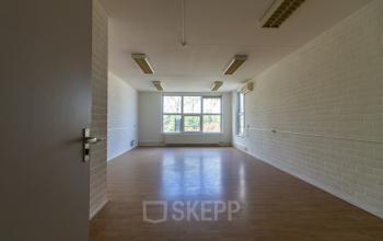 Interior view of an unfurnished office space at Middelweg 25, Beek Lb, featuring large windows and wooden flooring.