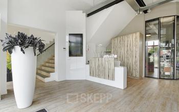 Sleek reception area in Bergen op Zoom office space rental at Bruinevisstraat 32, featuring a modern desk and elegant white vase.