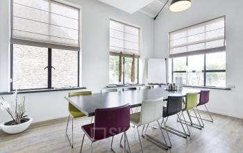 Spacious office space rental at Bruinevisstraat 32, Bergen op Zoom with modern furniture, large windows, and a well-lit conference room setup.