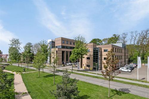 Exterior view of the office building at Rijtuigweg 10, Bergen op Zoom, showcasing a modern facade with surrounding greenery and nearby parking. Ideal for office space rental.