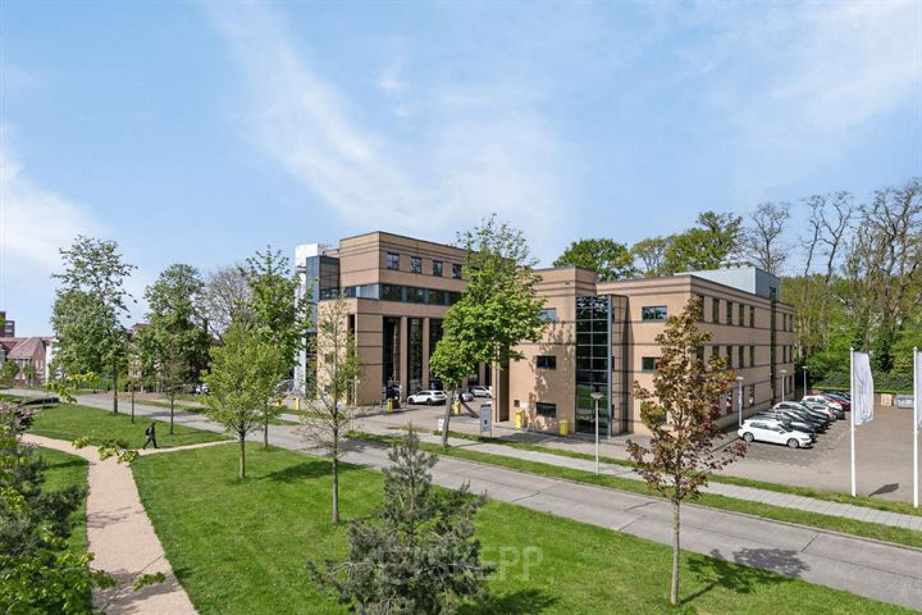 Exterior view of the office building at Rijtuigweg 10, Bergen op Zoom, showcasing a modern facade with surrounding greenery and nearby parking. Ideal for office space rental.