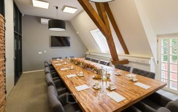 Modern office meeting room at Blokstallen 2B in Bergen op Zoom, featuring a large wooden conference table, comfortable chairs, and bright lighting, ideal for office space rental.