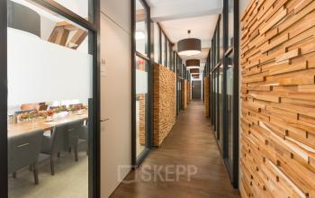 Modern office hallway at Blokstallen 2B, Bergen op Zoom with wooden paneling and glass-walled meeting rooms available for rent. Ideal office to rent for business operations.