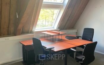 Bright office to rent at Blokstallen 2B, Bergen op Zoom, featuring wooden beams and desks beneath a large skylight, ideal for business activities.