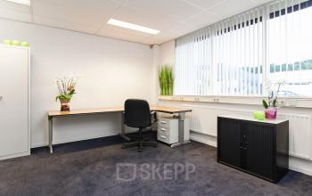 Furnished office to rent at Poortweg 1 in Bergen op Zoom, featuring a clean and bright workspace with a large window, desk, chair, and cabinet.