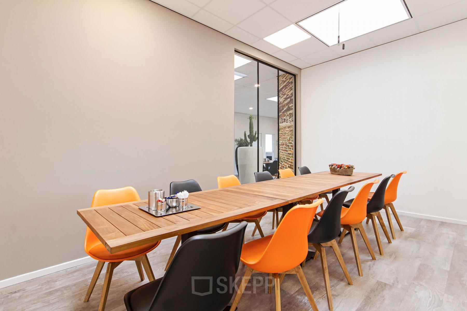 Office to rent located at Poortweg 1, Bergen op Zoom, featuring a long wooden table and colorful chairs in a bright and modern meeting room.