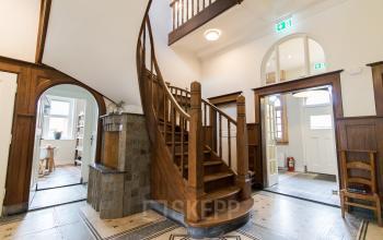 Interior view of office space with a wooden staircase and tiled floor at Prins Bernhardlaan 64, Bergen op Zoom.