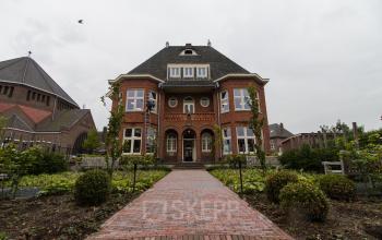 Exterior of office building for rent at Prins Bernhardlaan 64, Bergen op Zoom, showcasing a historic brick facade with surrounding greenery.