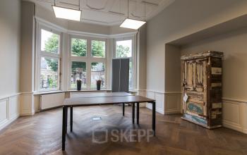 Office space rental at Prins Bernhardlaan 64, Bergen op Zoom featuring a furnished workspace with a large window and wooden flooring.