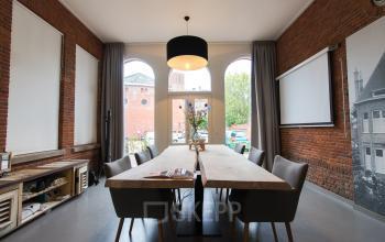 Conference room with wooden tables, modern chairs, and large windows at Prins Bernhardlaan 64, Bergen op Zoom.