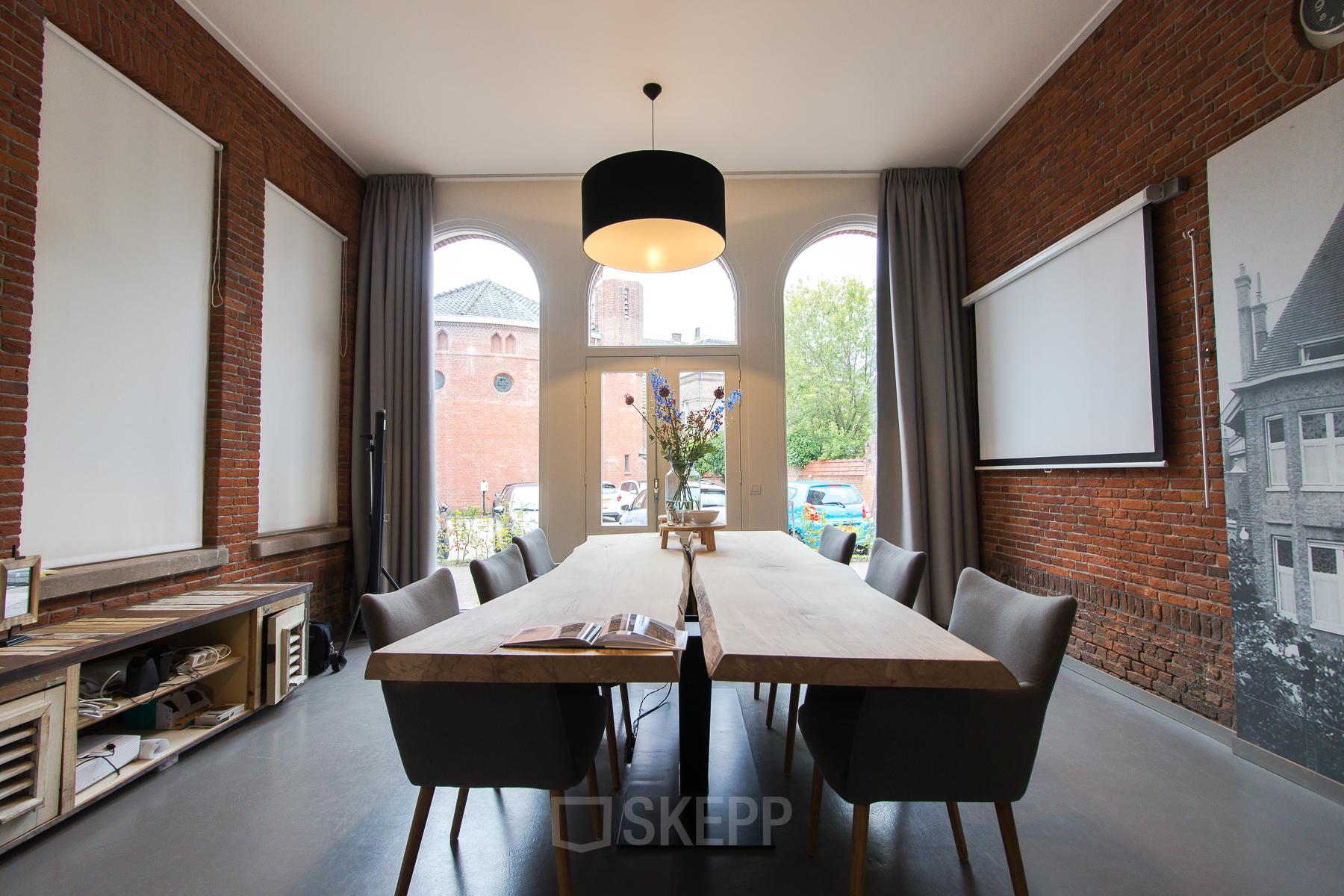 Conference room with wooden tables, modern chairs, and large windows at Prins Bernhardlaan 64, Bergen op Zoom.