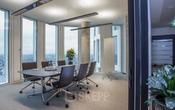 Innenansicht eines modernen Konferenzraums im Bürogebäude Kurfürstendamm 11, Upper West Tower in Berlin Charlottenburg, mit großen Fenstern und einer Aussicht auf die Stadt. Büromöbel und Pflanzen dekorieren den Raum.