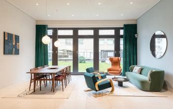 Büro mieten in der Knesebeckstraße 62, Berlin Charlottenburg. Heller Raum mit modernem Mobiliar und großen Fenstern. Ein langer Tisch mit Stühlen und eine gemütliche Sitzecke vorhanden.