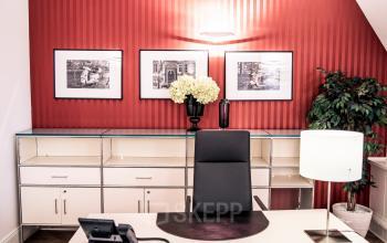 Stilvolles Büro mieten am Kurfürstendamm 194 in Berlin Charlottenburg mit modernem Schreibtisch, dekorativer Beleuchtung und roten Akzentwänden.