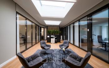 Moderner Büroraum am Kurfürstendamm 15 in Berlin-Charlottenburg mit stilvollen Sitzecken und Glaswänden. Ideal zum Büro mieten für professionelle Arbeitsumgebungen.