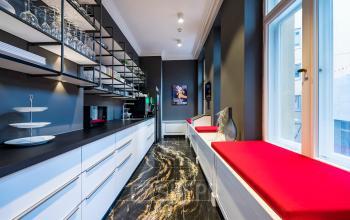 Moderne Küche im Bürogebäude am Kurfürstendamm 15 in Berlin Charlottenburg, mit schwarzen und weißen Elementen sowie roten Sitzpolstern. Ideal, um Bürofläche zu mieten.