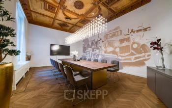 Eleganter Konferenzraum mit großem Holztisch und stilvollen Stühlen in Berlin Charlottenburg. Die üppige Decke und moderne Beleuchtung bieten eine inspirierende Atmosphäre, ideal zum Büroraum mieten.