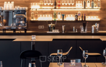 Moderne Bürofläche in der Koppenstraße 93, Berlin Friedrichshain, mit Barbereich, hohen Tischen und eleganter Beleuchtung. Perfekt zum Büroraum mieten.