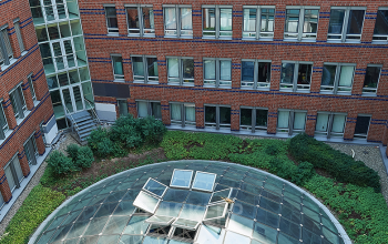 Innenhof von einem Bürogebäude in der Koppenstraße 93, Berlin Friedrichshain, mit einer verglasten Kuppel und umgeben von roten Backsteinmauern.