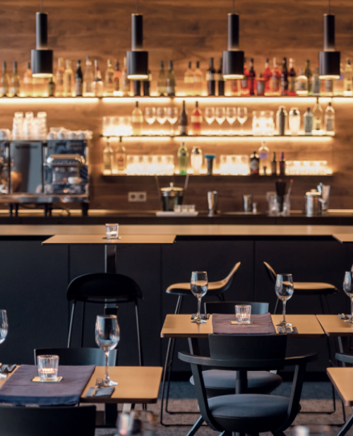 Moderne Bürofläche in der Koppenstraße 93, Berlin Friedrichshain, mit Barbereich, hohen Tischen und eleganter Beleuchtung. Perfekt zum Büroraum mieten.