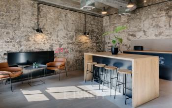 Moderner Büroraum in Berlin Friedrichshain, Köpenicker Straße 40-41, mit rustikaler Ziegelwand, Bartresen und bequemen Sitzgelegenheiten.